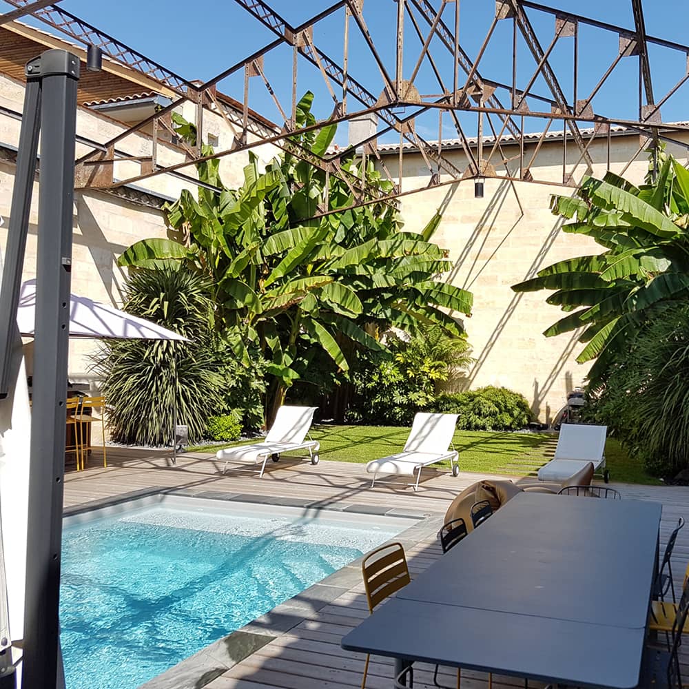 Jardin aménagé par notre architecte paysagiste, on y voit une terrasse en bois autour d'une piscine et divers massifs paysager