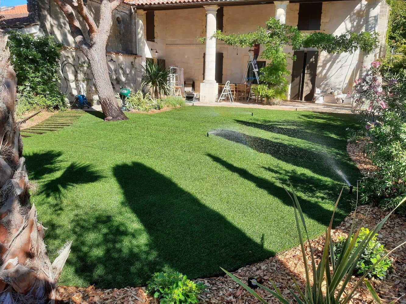 Jardin aménagé avec des massifs, un gazon naturel en plaque, une pose d'arrosage et la végétalisation de mur 