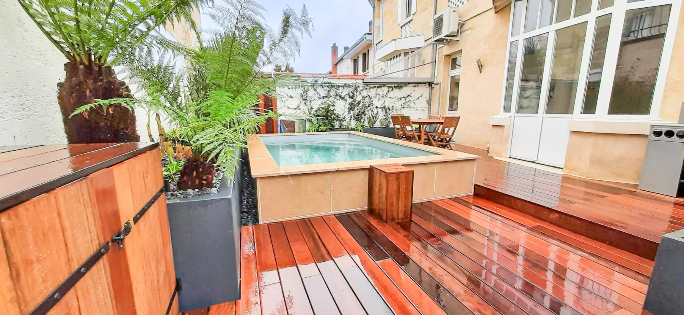 Aménagement d'une terrasse en bois exotique, ITAUBA, avec une piscine et des jardinières.