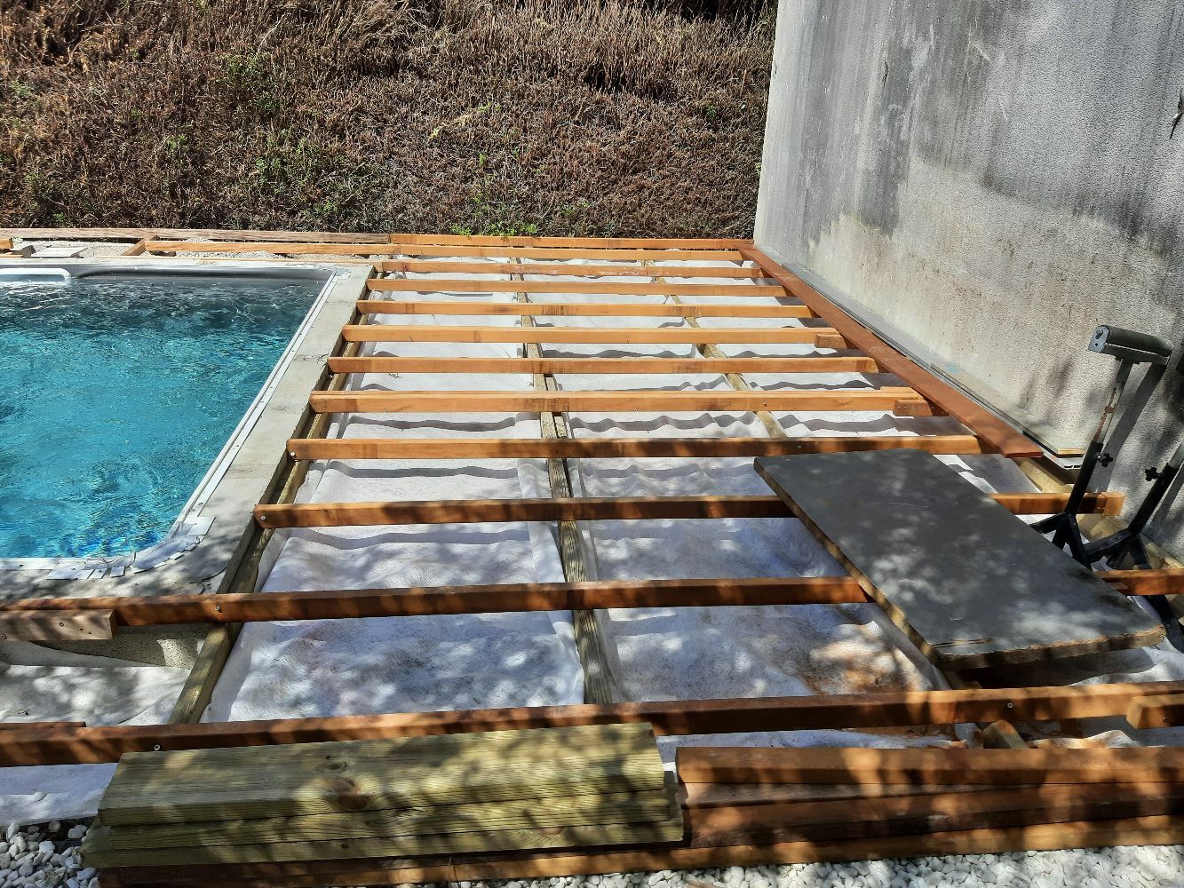 Pose des fondations composants la futur terrasse en bois exotique, avec la mise en place du geotextile