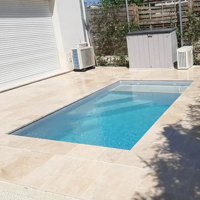 Photo d'une terrasse en travertin beige autour d'une piscine