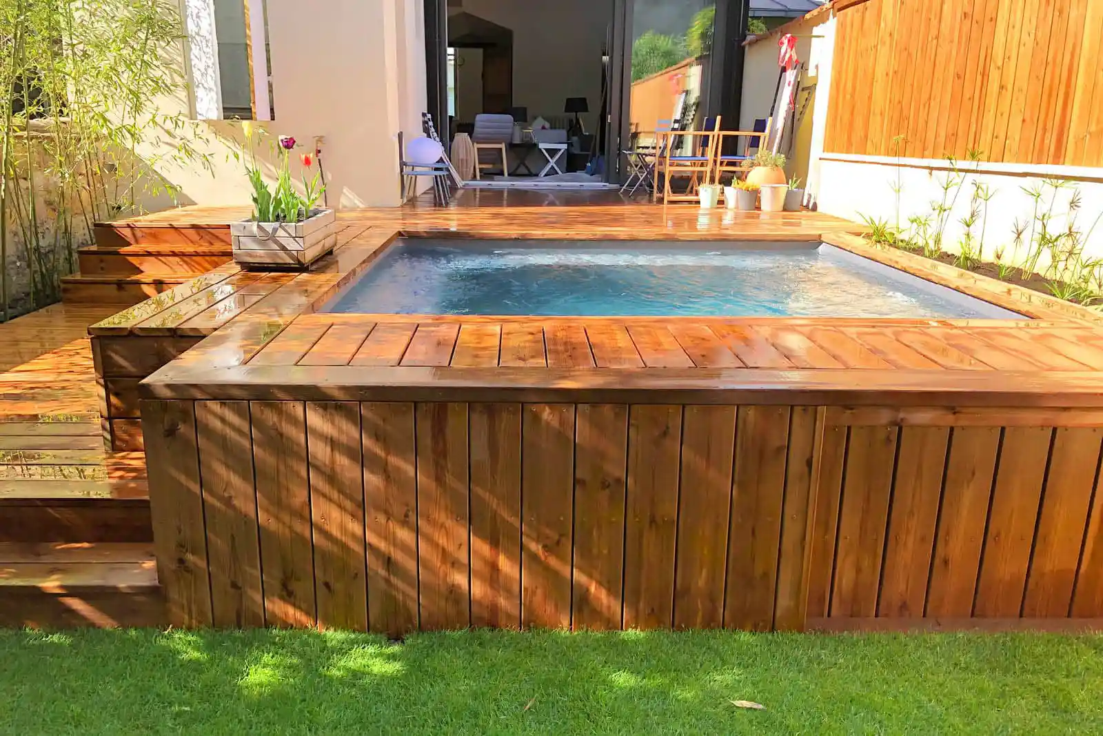 Aménagement d'un jardin avec une piscine implantée dans une terrasse en bois